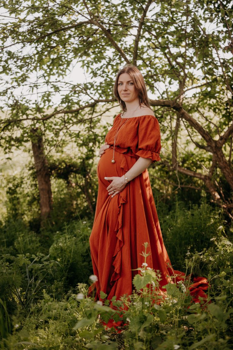femme enceinte, posant pour une séance photo grossesse en extérieur dans la campagne en Mayenne. Avec une robe bohème terracotta